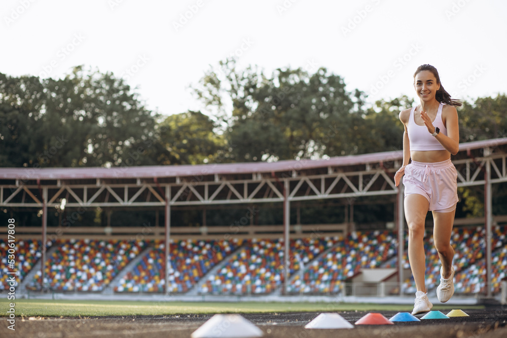 Woman running on track at the stadium using barriers