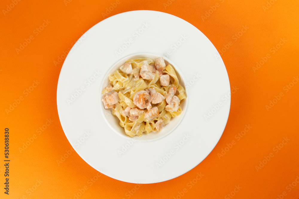 Pasta with salmon in a plate on an orange background. Pasta with salmon in a plate on an orange background.