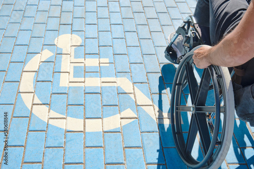 Foto disabled person in a wheelchair walking past a disabled person parking sign