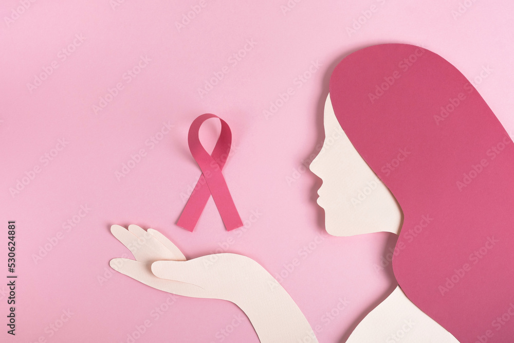 Breast cancer awareness concept. Womans head silhouette made from paper with pink ribbon on pastel background. Top view, copy space Breast cancer awareness concept. Womans head silhouette made from paper with pink ribbon on pastel background. Top view, copy space