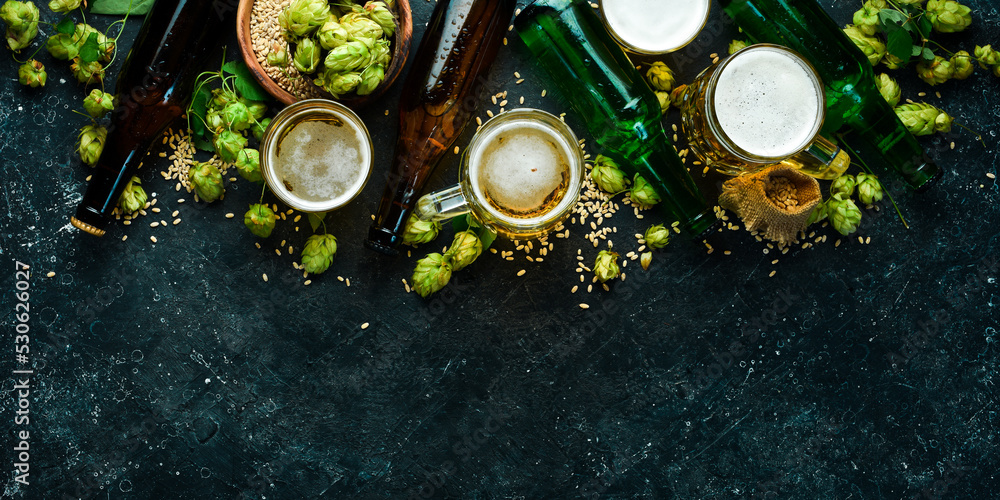 Fresh beer in bottles and glasses on a black stone background. Banner. Fresh beer in bottles and glasses on a black stone background. Banner.