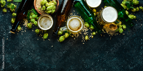 Fresh beer in bottles and glasses on a black stone background. Banner.