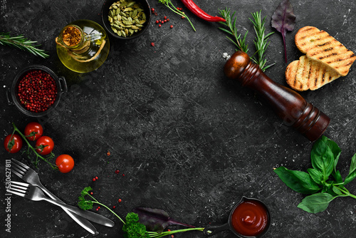 Black kitchen cooking background: vegetables, spices and kitchen utensils. Free space for text.
