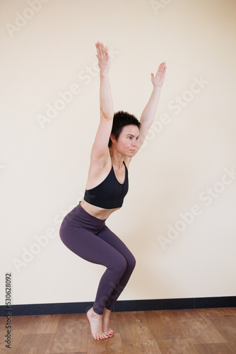 Young pretty yoga girl portrait, doing yoga poses indoors. Beautiful brunette short-haired woman doing pilates exercises. Woman in sports suit meditating. Woman stretching alone, flexible and slim.