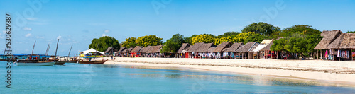 Sansibar, Kwale Island an der Küste der Insel. Dhows, Holzhütten am Strand, blauer Himmel und türkis-blaues Wasser, Panorama.