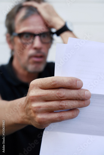 Ein Mann, erschrocken beim Lesen einer Rechnung