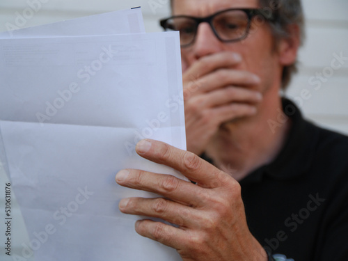 Ein Mann, erschrocken beim Lesen einer Rechnung