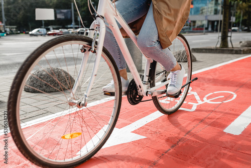 traffic, city transport and people concept - close up of woman cycling along red bike lane with signs of bicycles and two way arrows on street © Syda Productions