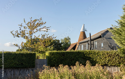 Small English oast, hop house in the kent countryside on a bright sunny evening