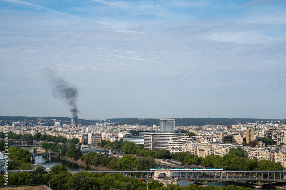 Black smoke of fire rising from a burning skyscraper, view from the Eiffel Tower in Paris
