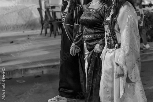black and white closeup of three courtesans holding hands dressed in medieval clothing during a historical parade © daniele russo