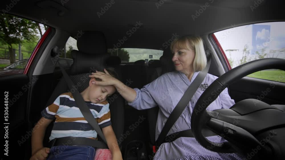 Grandmother and grandson are driving in the car. The boy fell asleep on the seat Grandmother and grandson are driving in the car. The boy fell asleep on the seat
