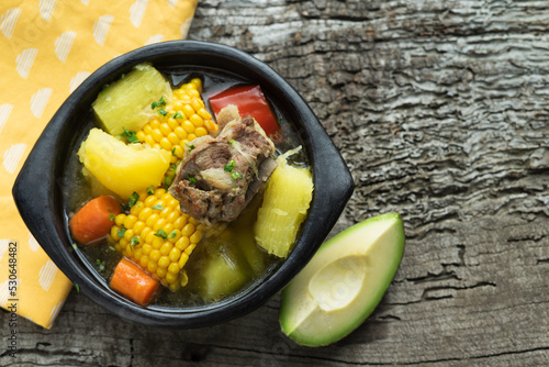 Sancocho, typical Colombian food in a black bowl on a rustic wooden background. photo