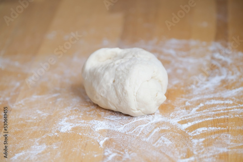 Dough lies in flour on wooden surface closeup