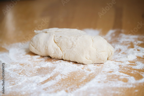 Dough on a wooden board with wheat flour