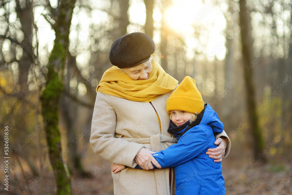 Little grandson and elderly grandmother during walking in autumn park. Friendship granny and grandchild. Little grandson and elderly grandmother during walking in autumn park. Friendship granny and grandchild.