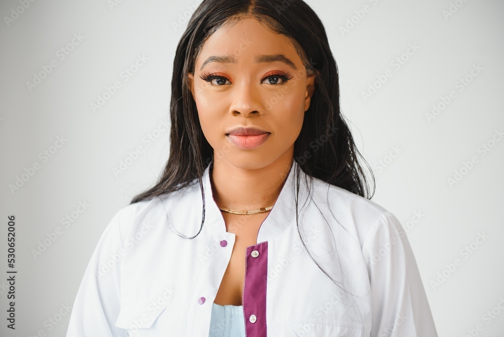Portrait of beautiful smiling female african american doctor standing in medical office. Health care concept, medical insurance, copy space. Portrait of beautiful smiling female african american doctor standing in medical office. Health care concept, medical insurance, copy space.