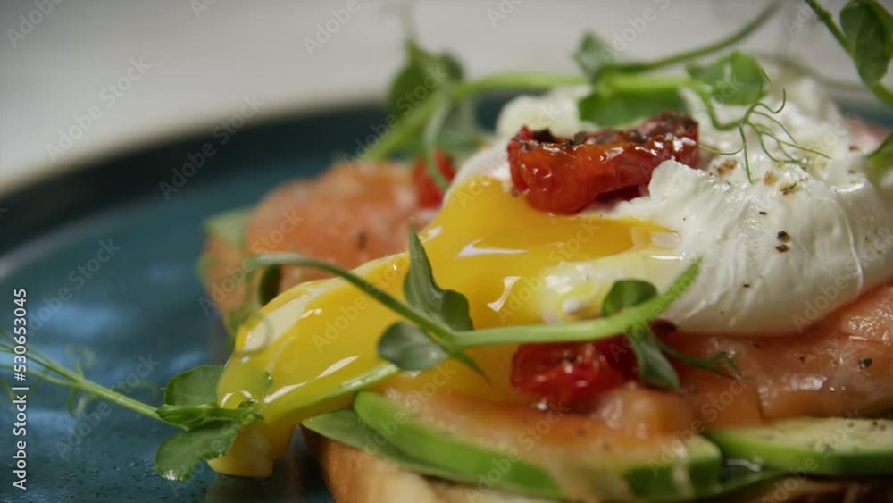 Close-up A poached egg is cut on a sandwich with salmon and avocado. Close-up A poached egg is cut on a sandwich with salmon and avocado.