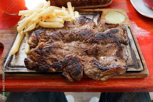 Appetizing beef churrasco, sprinkled with sliced fried potatoes. POV.