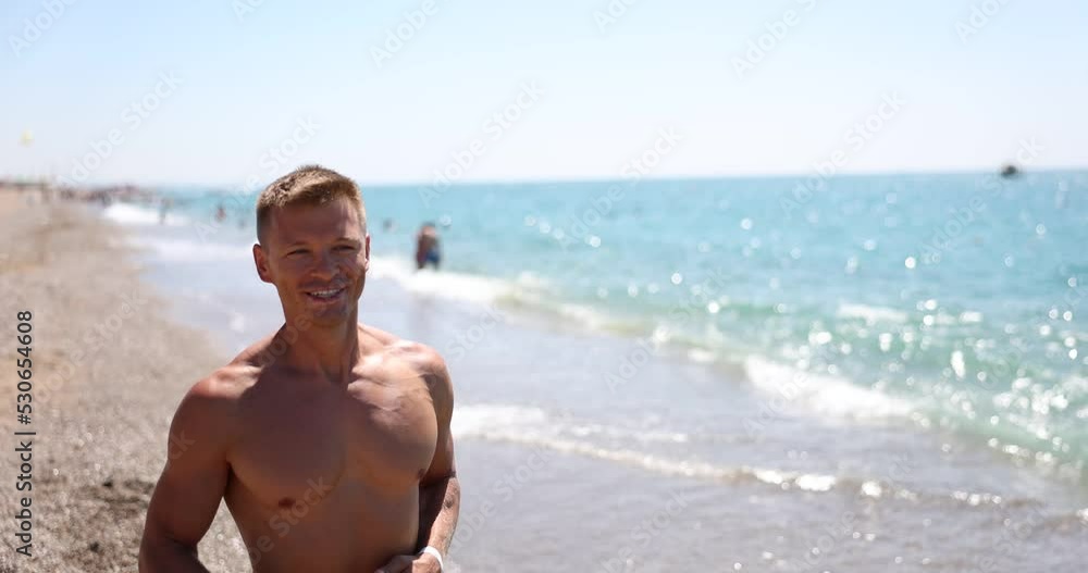 Smiling handsome man runs along sea on beach Smiling handsome man runs along sea on beach