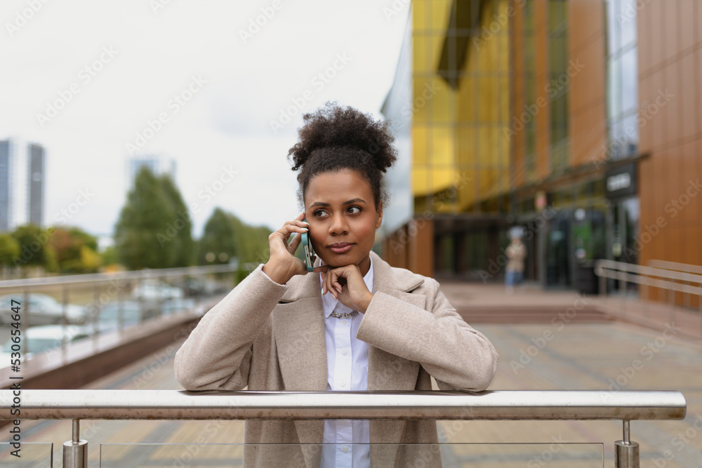 african american woman businessman concentratedly talking on a mobile phone on the background of an office building, business negotiations concert african american woman businessman concentratedly talking on a mobile phone on the background of an office building, business negotiations concert