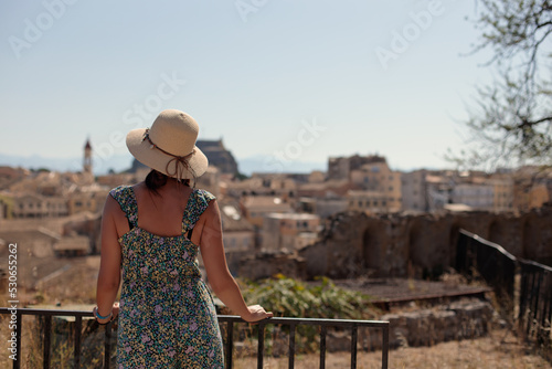 A tourist girl looks at the historic skyline of Corfu town in Greece. Back view of traveler girl  vacation concept.