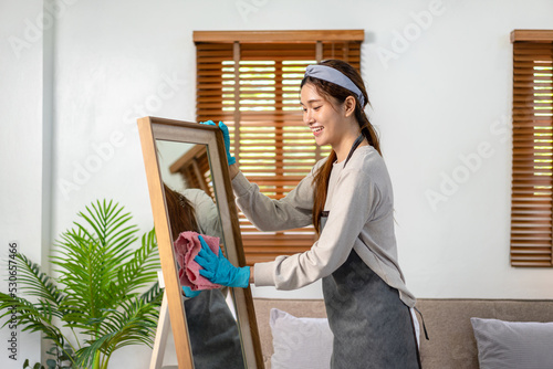 Quadro su tela Housekeeper is wearing protective gloves and using microfiber cloth to cleanups