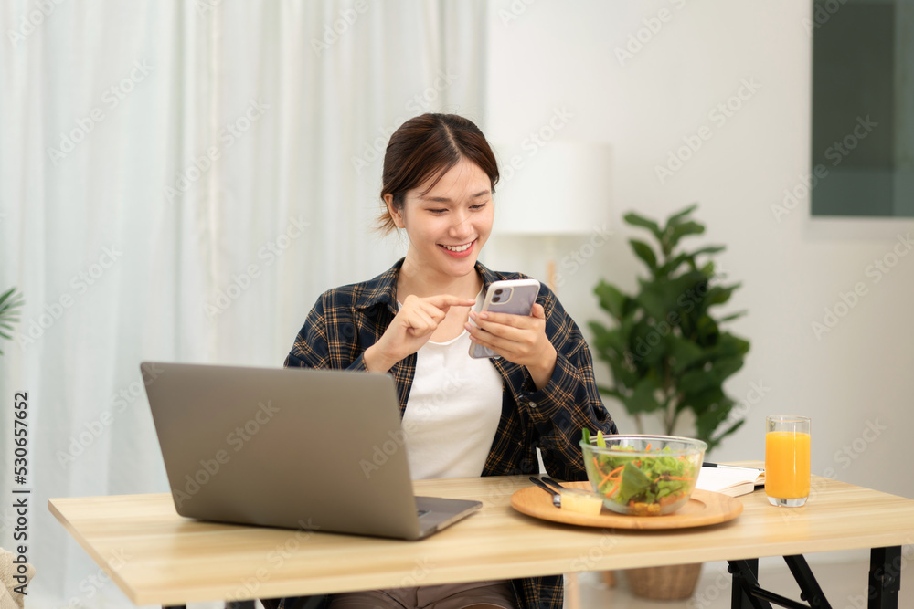 Teenage girl is taking a break to eating breakfast and chatting with friends on smartphone after using