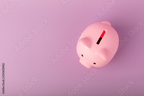 Piggy bank on a lilac texture background. Close-up. Space for copy. Flat lay. Savings and accumulation concept.
