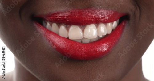 Close up view of a black woman with red lipstick blowing a kiss then smiling. Isolated on a white background.