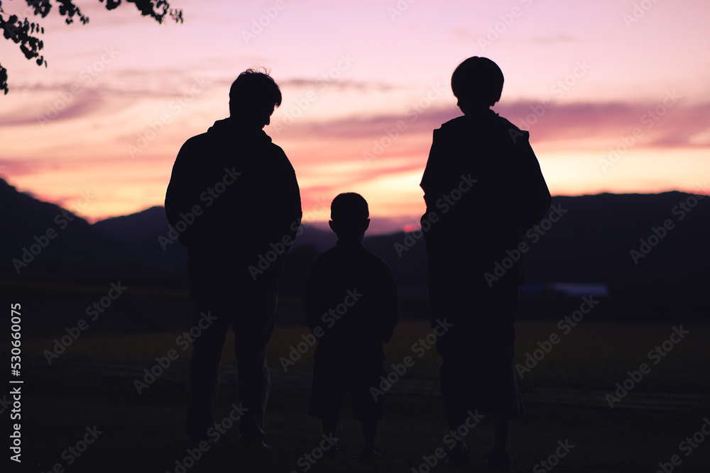 夕焼けを眺める家族のシルエット