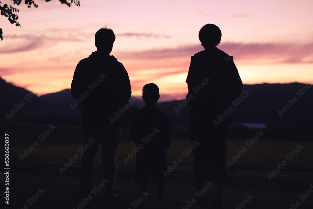 夕焼けを眺める家族のシルエット