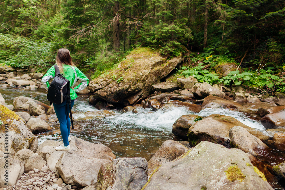 Back view of traveler hiker with backpack admiring landscape by mountain river in Carpathian forest. Active lifestyle Back view of traveler hiker with backpack admiring landscape by mountain river in Carpathian forest. Active lifestyle