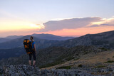A Female backpacker admiring mountains at sunset