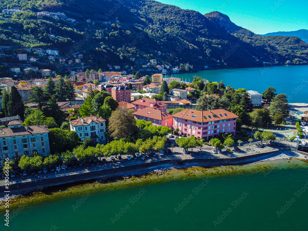 Aerial view of Lake Como. city ​​center. A local ferry arrives in the city. Bell tower. Tourism and romance. Mountains around the lake. Red roofs. Green Planet. Sailing yacht. Italy, Bellano, 10.2022