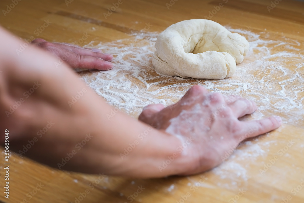 Close up of hands in flour lean on the table next to roll of dough Close up of hands in flour lean on the table next to roll of dough