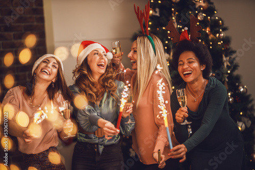Multiethnic Female Friends Playing With Sparklers And Making Toast As During Christmas Home Party