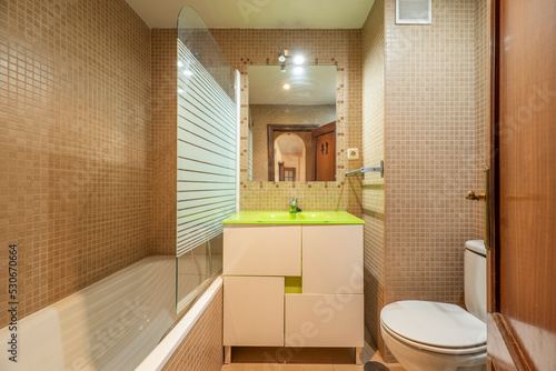 Small bathroom with white wood vanity with frameless mirror and green glass sink
