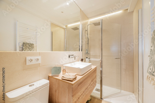 Bathroom with wooden vanity with frameless mirror