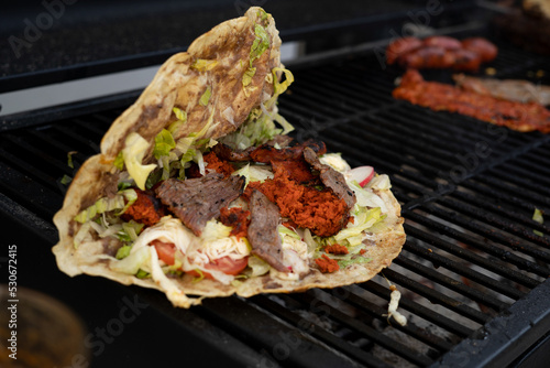 top view of Mexican food Tlayuda de cecina y chorizo and its preparation ingredients on a wooden table, frijoles, beans, cecina, sausage, lettuce, sauce, fruit water photo