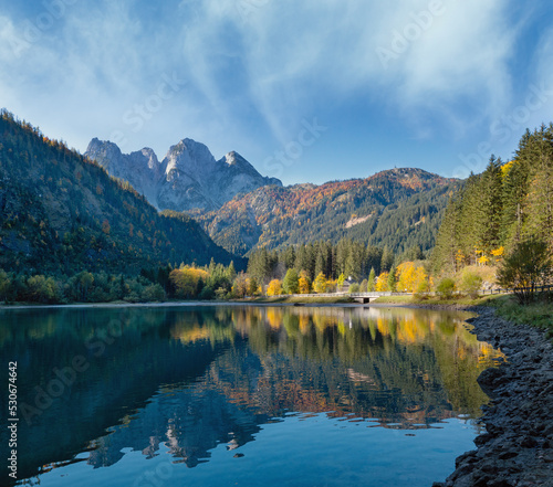 Peaceful autumn Alps mountain lake with clear transparent water and reflections. Gosauseen or Vorderer Gosausee lake, Upper Austria. Dachstein summit and glacier in far.