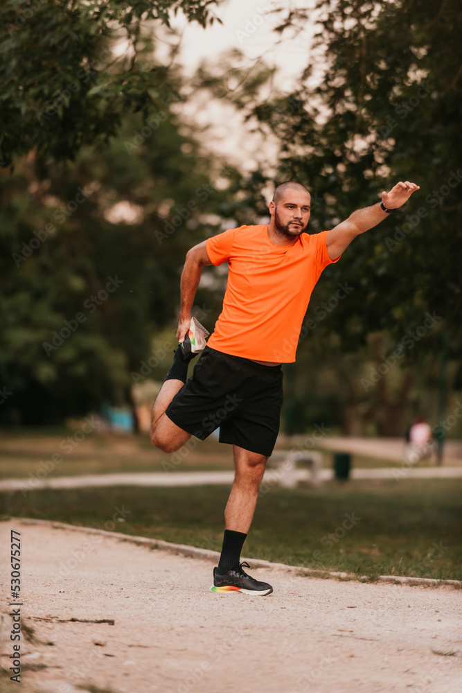 Happy positive sportsman during outdoor workout, man wearing sports outfit warming up muscles,enjoying active lifestyle outside in park