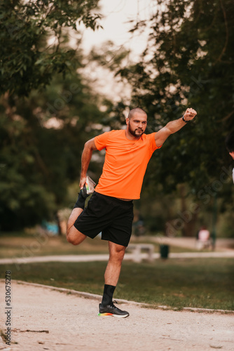 Happy positive sportsman during outdoor workout, man wearing sports outfit warming up muscles,enjoying active lifestyle outside in park