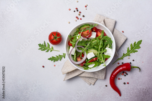 Healthy vegetarian salad with fresh arugula, cherry tomatoes, soft cheese and cucumbers