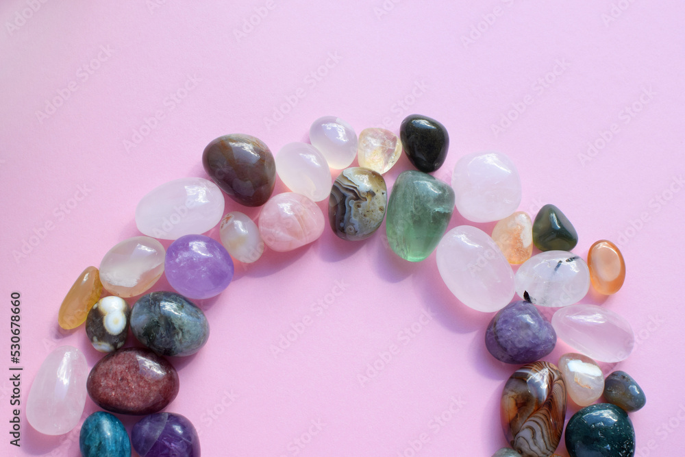 The circle is lined with natural minerals. Semi-precious stones of different colors, raw and processed. Amethyst, rose quartz, agate, apatite, aventurine on a pink background. The circle is lined with natural minerals. Semi-precious stones of different colors, raw and processed. Amethyst, rose quartz, agate, apatite, aventurine on a pink background.