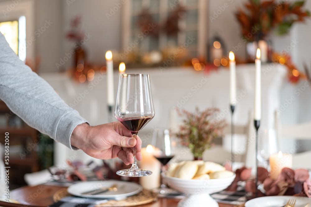 Man setting a wineglass on Thanksgiving dinner table