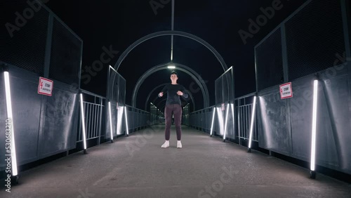 popping dance style performance in urban scape, young talented woman is dancing like robot in tunnel photo