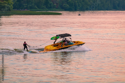 A boat pulls a person over the waves on a wakeboard. Wakeboarding at sunset. photo