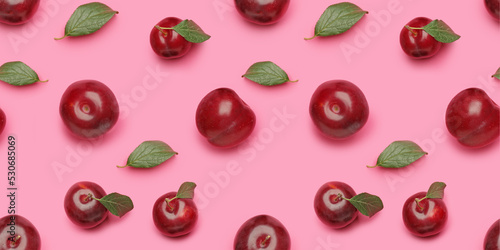 Many ripe plums on pink background. Pattern for design