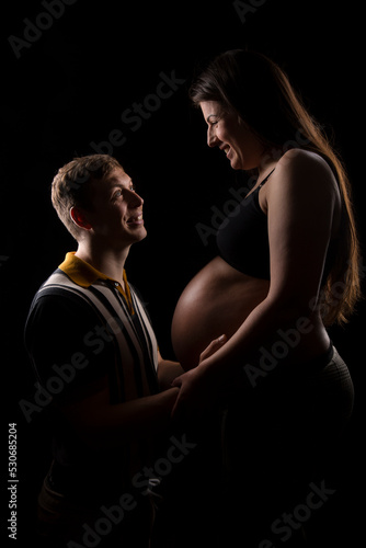 Young parents to be looking at each other lovingly as they embrace there unborn child in the mothers baby bump.
